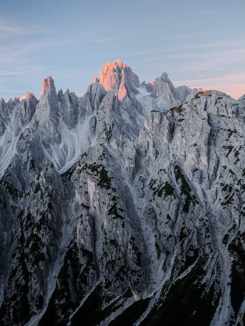 Sharp gray limestone spires of the Cadini di Misurina catching the first pink light of sunrise.
